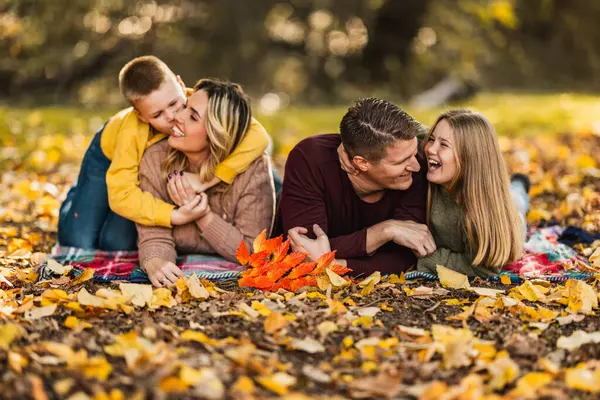 Dört kişilik mutlu bir aile güzel bir günde sonbahar parkında eğleniyor ve oyun oynuyor.. 