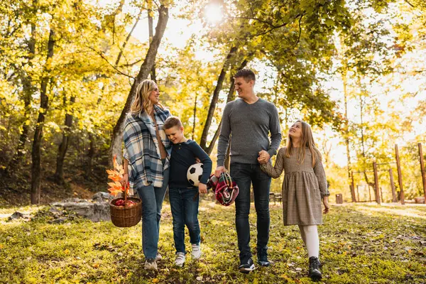 Mutlu bir aile el ele tutuşup ağaçların etrafındaki güzel bir sonbahar parkında yürüyor.. 