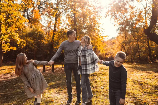 Mutlu bir aile, sonbaharda parkta neşeli bir anın tadını çıkarıyor.. 