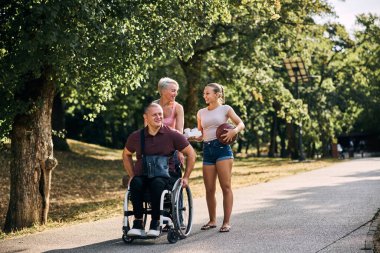 Mutlu bir aile, dışarıda tekerlekli sandalyedeki bir adamla güzel vakit geçirir.. 