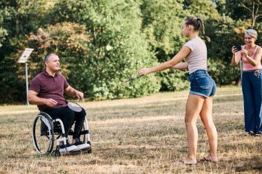 Mutlu bir aile güneşli parkta badminton oynarken eğleniyor.. 
