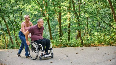 İnsanlar tekerlekli sandalyedeyken güzel parkta yürüyen bir çift.. 