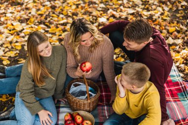 Mutlu, neşeli bir aile parkta piknik yapıyor ve sonbahar günü parkta elma yiyor.. 