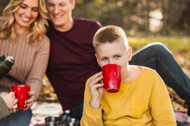 Aile güzel bir sonbahar gününde sıcak çay içerken parkta piknik yapıyor.. 