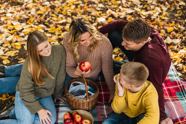 Mutlu, neşeli bir aile parkta piknik yapıyor ve sonbahar günü parkta elma yiyor.. 