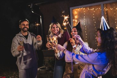 Mutlu arkadaşlar doğum gününü fıskiyelerle kutlar. Neşeli ve gülümserler..