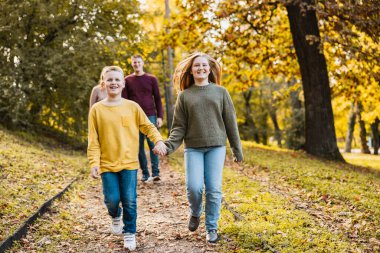 Dört kişilik neşeli bir aile güzel bir sonbahar parkında güzel bir yürüyüş yapıyor.. 