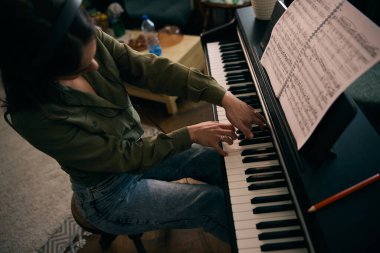 Piyano çalan genç ve güzel bir kadın evde notalara odaklanıyor.. 