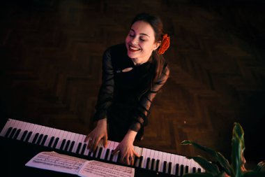 Kızıl saçlı genç bir kadın tutkuyla piyano çalıyor ve evde eğleniyor.. 