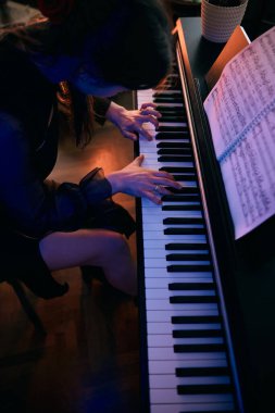 Evde tutkuyla piyano çalan genç bir kadın..