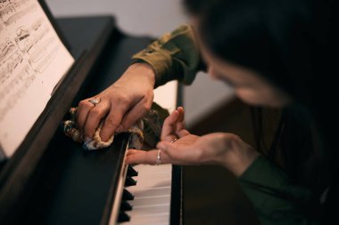 Güzel genç bayan sıcak evinde piyanoyu derinden temizliyor.. 