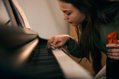 Güzel genç bayan sıcak evinde piyanoyu derinden temizliyor.. 