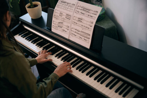 Молодая женщина со страстью играет на пианино, наслаждается им и запечатлевает момент дома. 