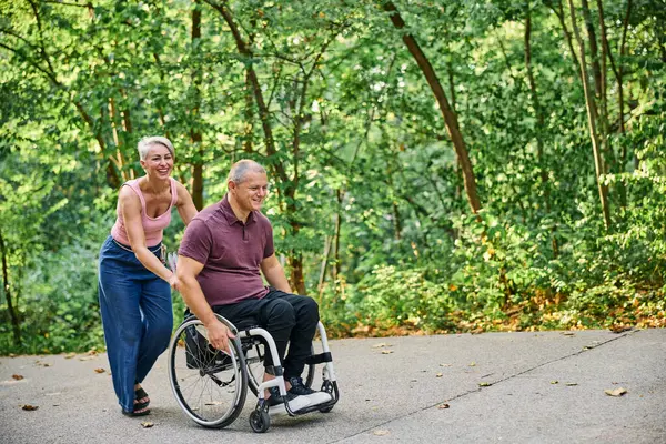 İnsanlar tekerlekli sandalyedeyken güzel parkta yürüyen bir çift.. 