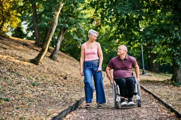 Bir çift, refakatçilik ve kapsayıcılığın altını çizerek, lüks bir parkta sakin bir şekilde yürümekten zevk alır..