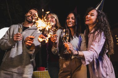 Mutlu arkadaşlar doğum gününü fıskiyelerle kutlar. Neşeli ve gülümserler..