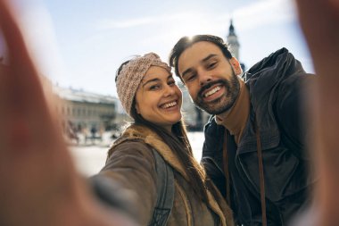 Mutlu, gülümseyen bir çift güneşli bir günde kameraya bakarken selfie çekiyor.. 