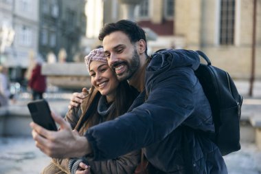 Yeni şehirde selfie çeken gülümseyen turist çift birlikte keşfe çıkıyorlar..