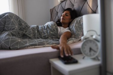 Komodinin üzerinde telefona uzanan bir el sahnesi.. 