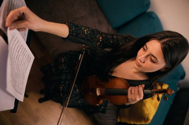Kemancı keman çalmaya hazırlanıyor, notalara bakıyor..