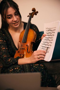 Gülümseyen bir kız keman çalma notalarını dikkatlice açıklar.