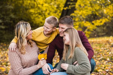 Dört kişilik mutlu bir aile ve sonbahar günü güzel bir parkta eğleniyorlar.. 