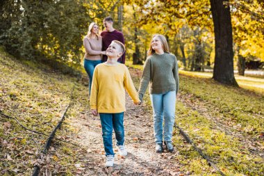 Dört kişilik neşeli bir aile güzel bir sonbahar parkında güzel bir yürüyüş yapıyor.. 