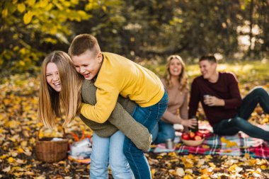 Erkek ve kız kardeş sonbahar günü parkta oynarken ebeveynler onları izliyor.. 