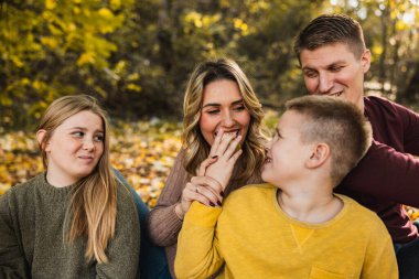 Dört kişilik neşeli aile sonbahar günü parkta eğleniyor..