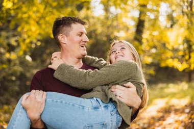 Gülümseyen baba-kız parkta eğlenirken baba kızını sonbahar parkında tutuyor.. 