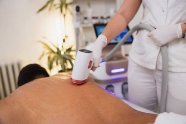 Güzellik uzmanının profesyonel güzellik kliniğinde sırtına lazer epilasyonu yapması.. 