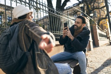 Neşeli bir adam güneşli bir sokakta açık havada bir kadının samimi bir fotoğrafını çekmekten hoşlanır.. 