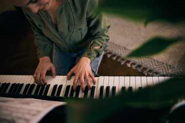 Tutkuyla piyano çalan, eğlenen ve evde kulaklık takan genç bir kadın.. 