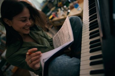 Genç bir kadın piyano çalarken kağıda nota yazıyor.. 