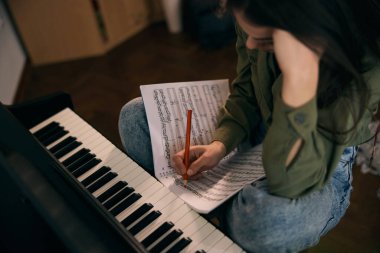 Genç bir kadın piyano çalarken kağıda nota yazıyor.. 