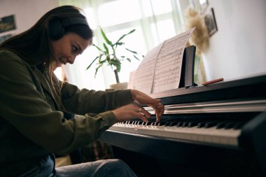 Piyano çalan genç ve güzel bir kadın evde notalara odaklanıyor.. 