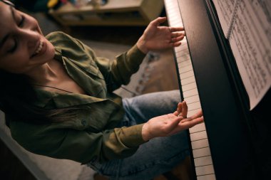 Piyano çalan genç ve güzel bir kadın evde notalara odaklanıyor.. 