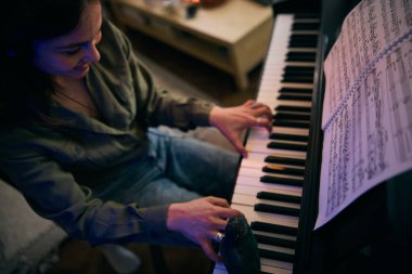 Evde tutkuyla piyano çalan genç bir kadın..