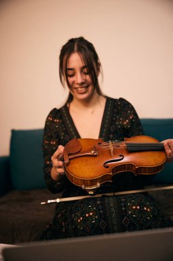 Genç bir kadın keman almış, çok mutlu ve heyecanlı.
