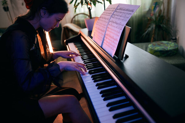 Молодая женщина играет на пианино со страстью дома.