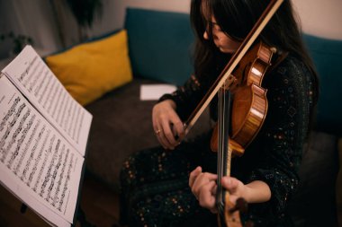 Gün boyunca her boş anında kemancı keman çalışmak için kullanır. Hoşuna gidiyor çünkü ünlü bir kemancı olmak istiyor.