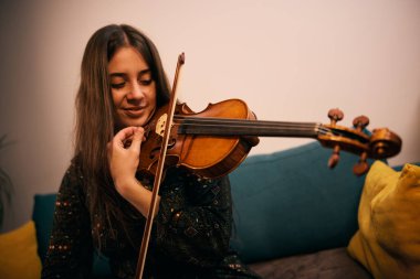 Kadın müzisyen evde keman çalıyor..