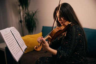 Gün boyunca her boş anında kemancı keman çalışmak için kullanır. Hoşuna gidiyor çünkü ünlü bir kemancı olmak istiyor.