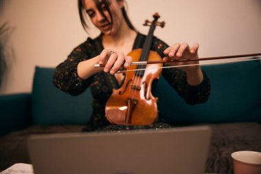 Keman öğretmeni öğrencilere çevrimiçi keman dersleri veriyor.