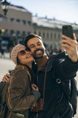 Mutlu, gülümseyen bir turist çifti. Yeni şehirde telefonla selfie çekiyor. Güneşli bir gün.. 