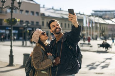 Mutlu, gülümseyen bir turist çifti. Yeni şehirde telefonla selfie çekiyor. Güneşli bir gün.. 