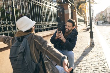 Neşeli bir adam güneşli bir sokakta açık havada bir kadının samimi bir fotoğrafını çekmekten hoşlanır.. 