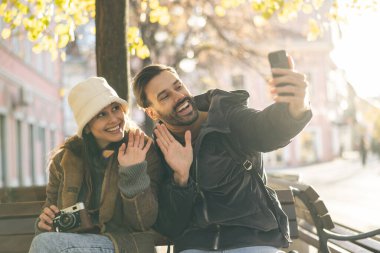 Parkta oturmuş telefonda sohbet eden neşeli bir çift..