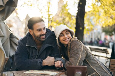 Gülümseyen çift açık havada kafede oturuyor ve birlikte güzel bir günün tadını çıkarıyor.. 
