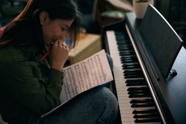 Genç bir kadın piyano çalarken kağıda nota yazıyor.. 